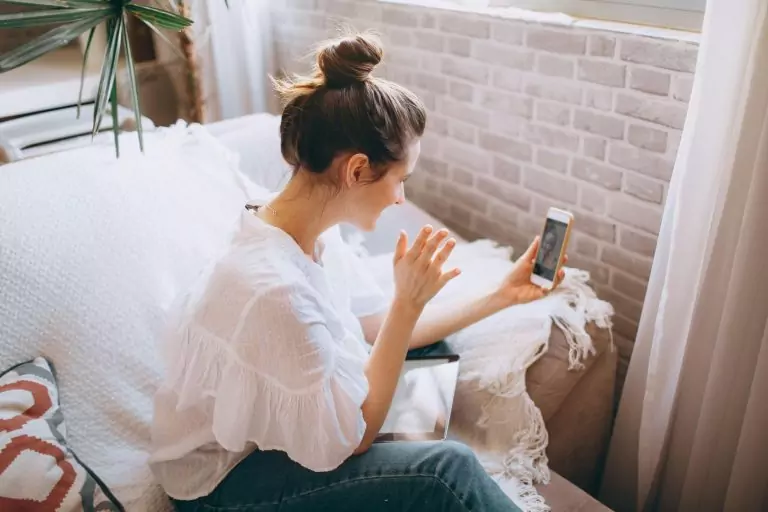 Femme en train de créer du contenu sur les réseaux sociaux via son téléphone.