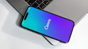Téléphone posé sur un ordinateur avec l'application Canva ouverte pour créer un logo.