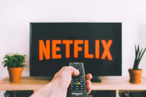 main tenant une télécommande et allumant la télévision pour regarder Netflix.