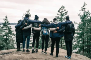 Groupe de randonneurs en train de s'enlacer devant un étang.