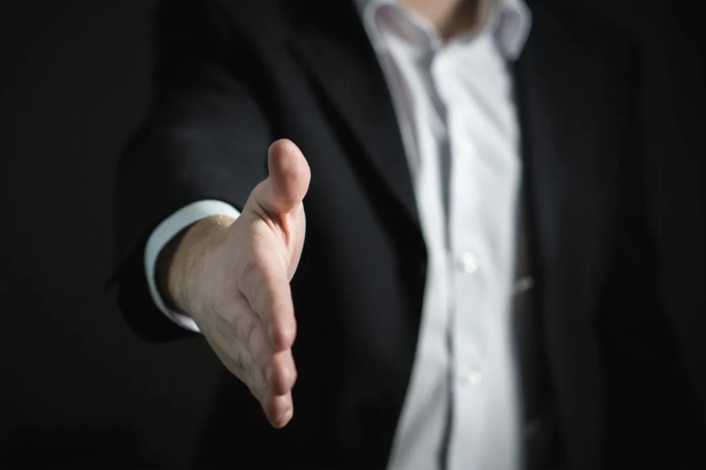 Homme en costume tendant la main, symbole d’accord, de partenariat ou d’accueil professionnel.
