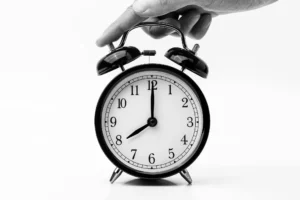 Horloge noir et blanc avec un doigt appuyant, illustrant la gestion du temps en communication.