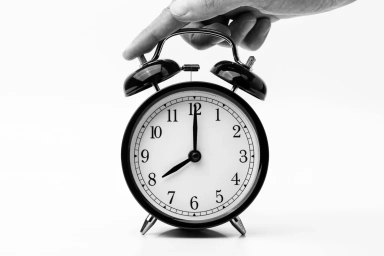 Horloge noir et blanc avec un doigt appuyant, illustrant la gestion du temps en communication.