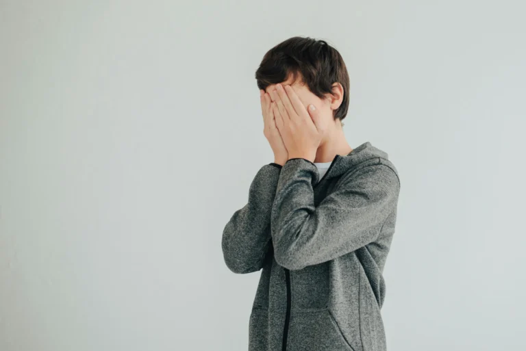 Jeune garçon stressé se cachant le visage, illustrant les blocages en communication ou le manque de confiance