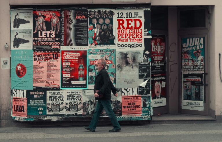 Homme marchant dans la rue devant des affiches de communication papier.